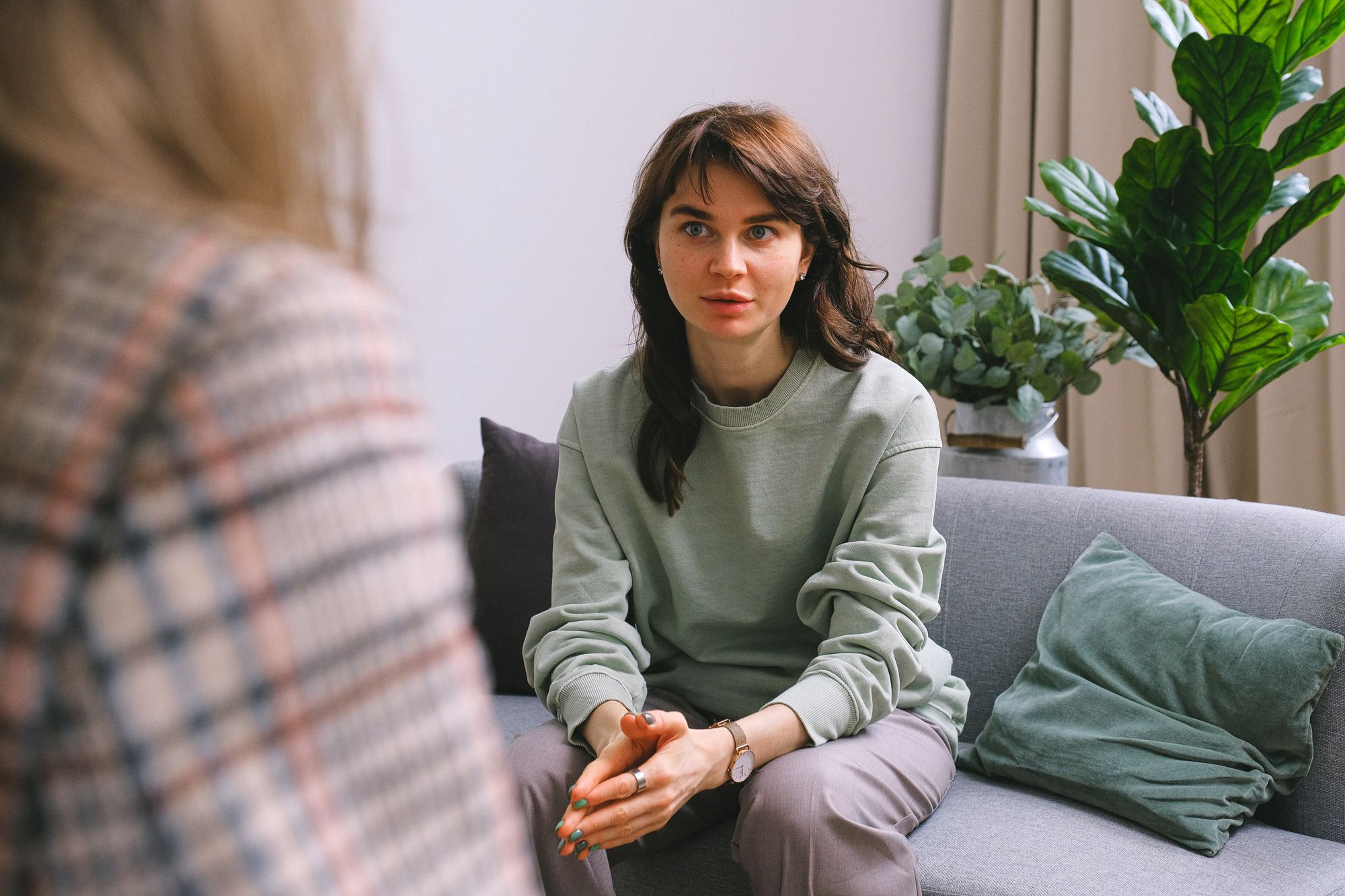 A woman seated on a sofa, engaged in a face-to-face conversation